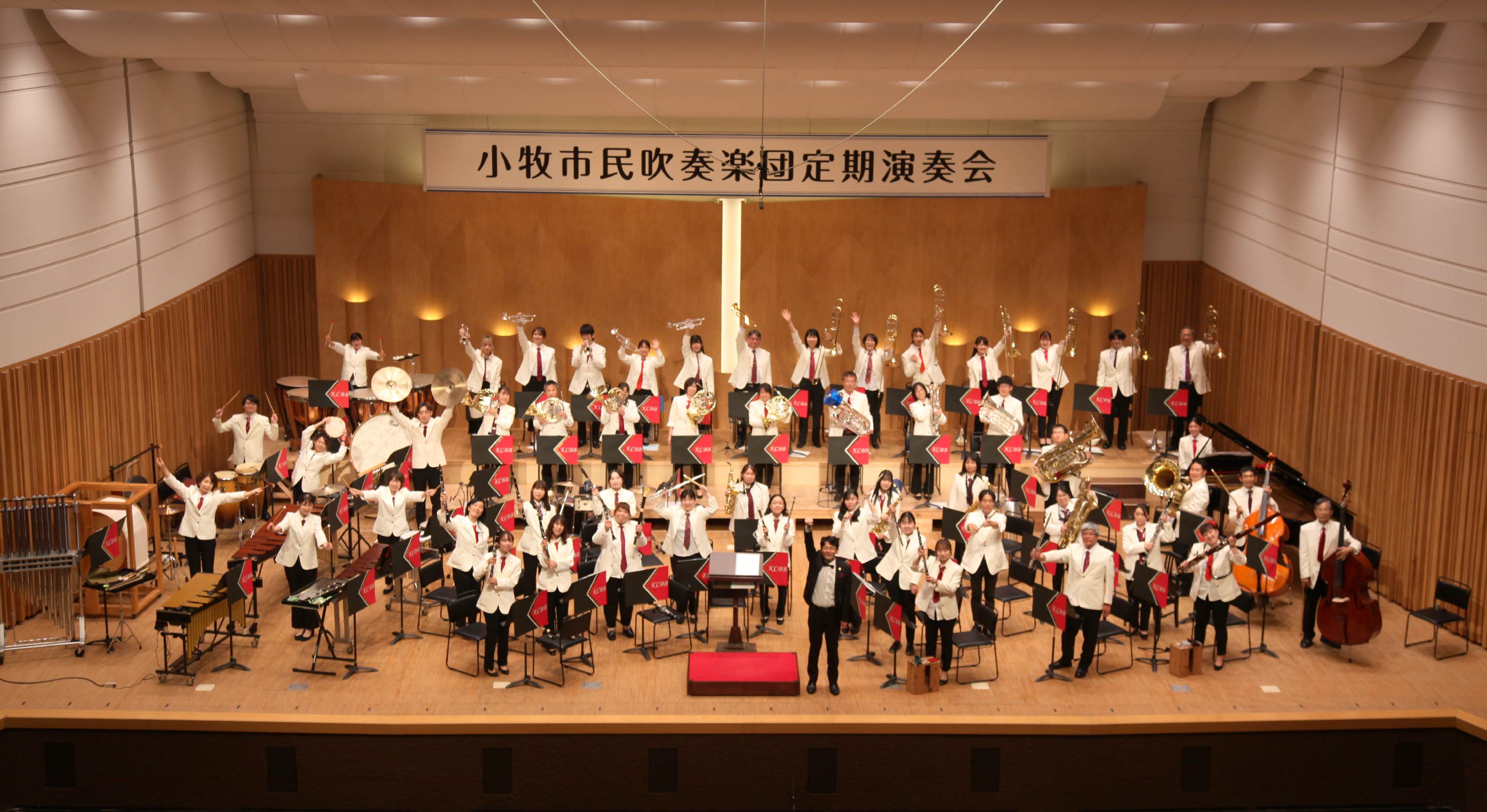 小牧市民吹奏楽団の定期演奏会の写真です。団員たちがカメラに向かってポーズを決めています。